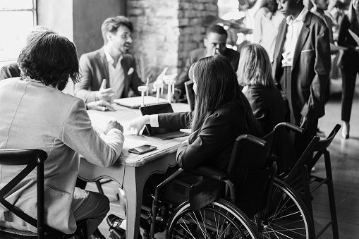 Multiracial business people working on sustainable innovation project - Focus on asian woman sitting on wheelchair - Black and white editing